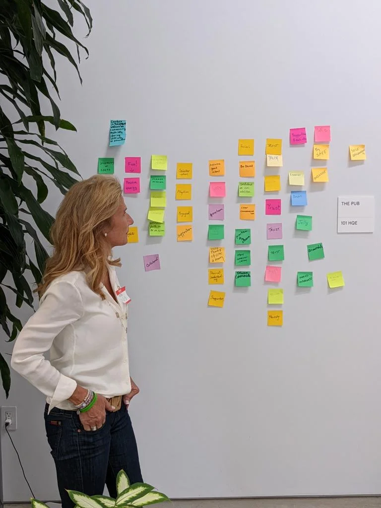 Petra Chequer reading a wall of sticky notes from a team session